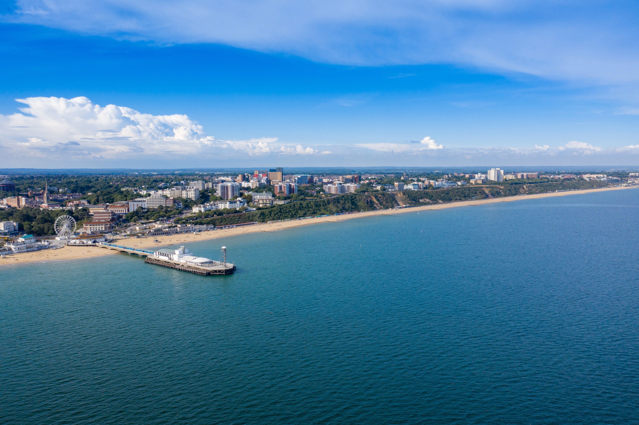 Aerial drone photo of the Bournemouth beach, Observation Wheel and Pier on a beautiful sunny summers day with lots of people relaxing and sunbathing on the British Dorset sandy beach and ocean